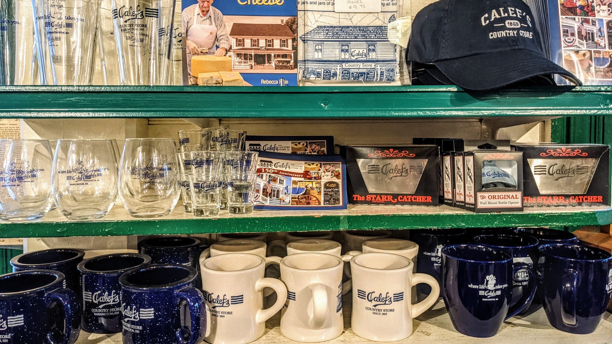 Calef's Merchandise including hats, bottle openers, coffee mugs, and camp mugs